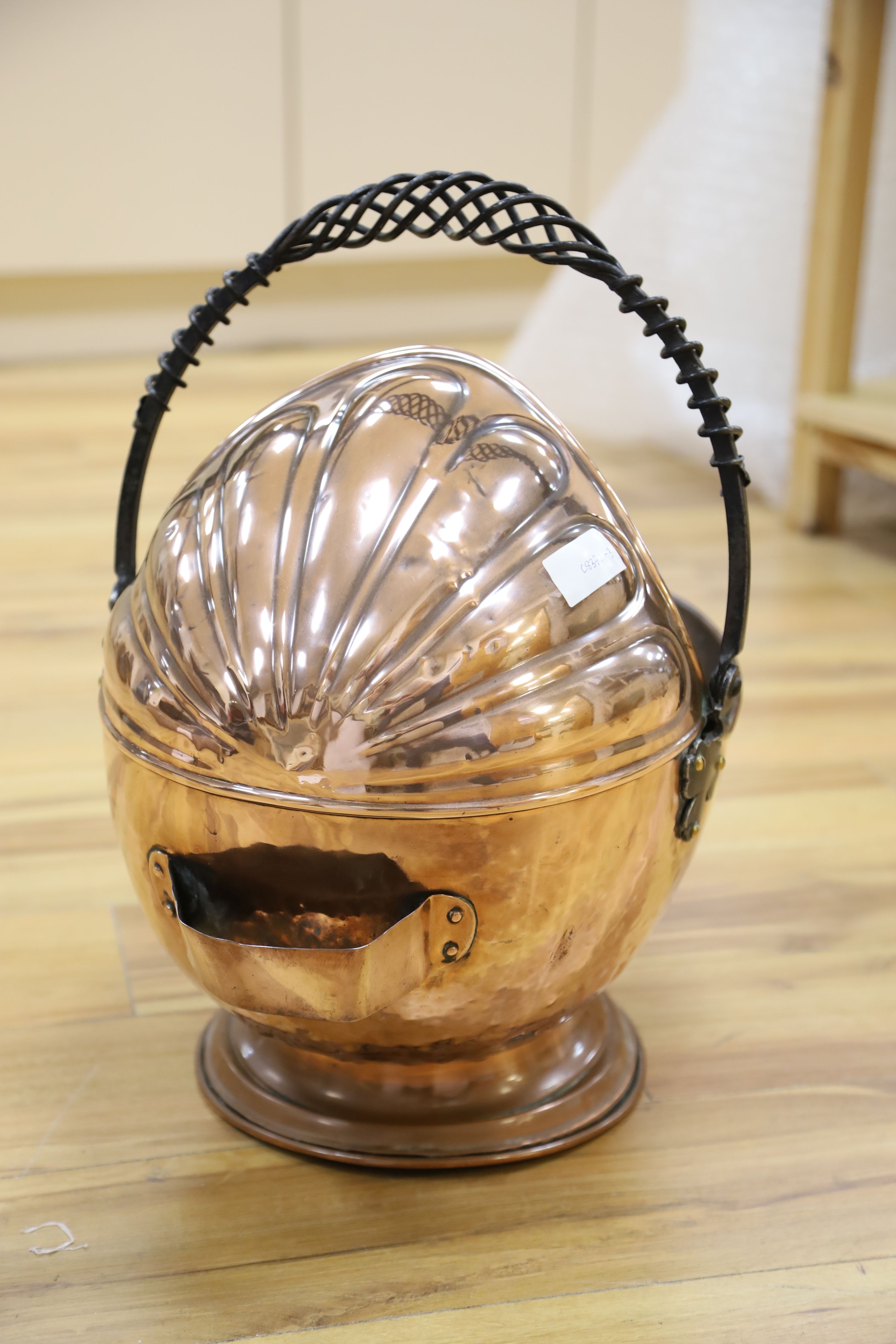 An Arts & Crafts planished copper coal scuttle, with wrought iron handle